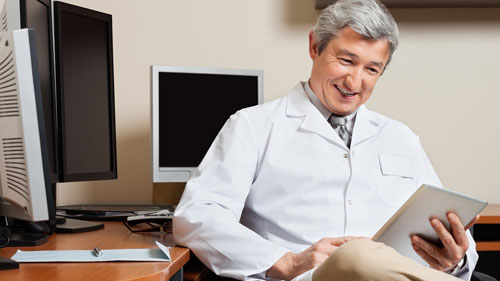 Physician Looking at Billing and Coding Records while Smiling
