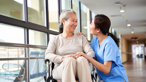 Physician Helping Older Woman in Wheelchair Smiling